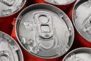 Group of red aluminum soda or cola cans in ice with water droplets