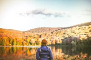 Serene young woman alone in nature surrounded by beautiful autumn colors.
