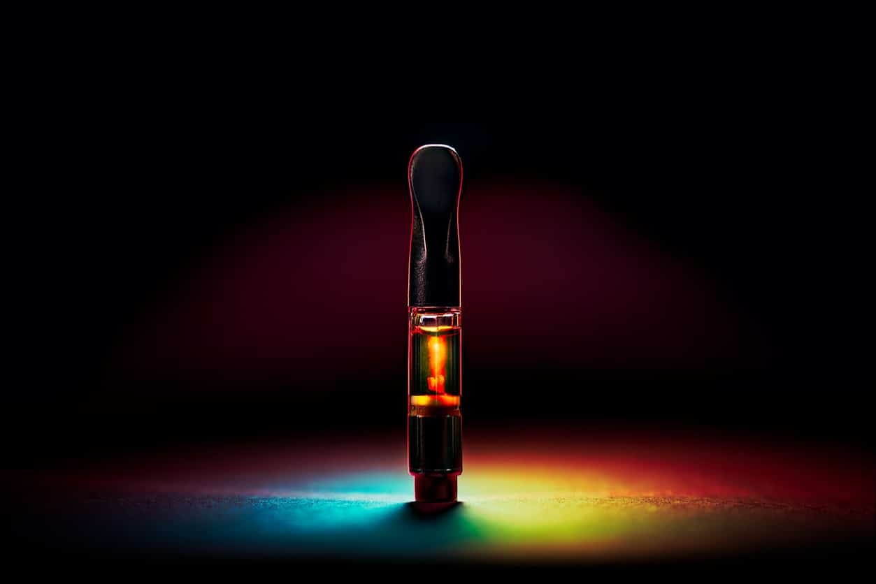 New Marijuana Vape Pen Cartridge with radiant rainbow lighting and dark background.