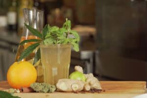 A healthy drink made of lime, ginger, and cannabis on a wooden surface